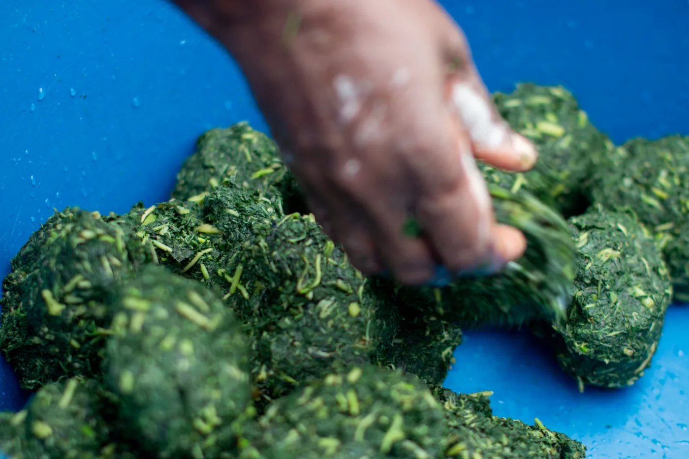 Fresh leafy ingredients being shaped by hand