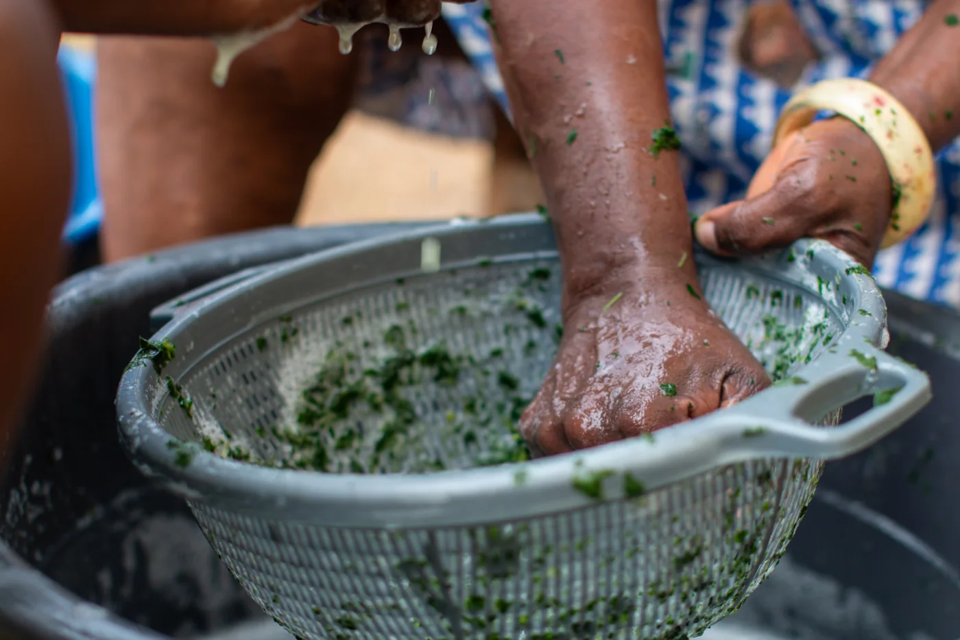 Hands washing fresh leafy ingredients in a colander